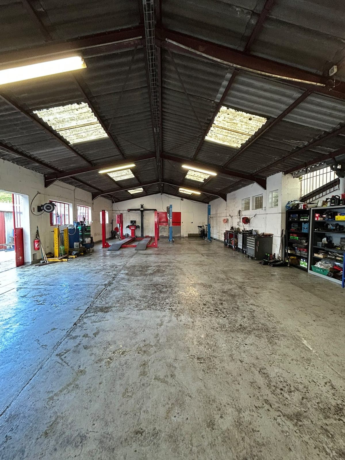 Vue d'ensemble de l'atelier : ponts élévateurs 2 et 4 colonnes, servantes d'outils et rayonnages.