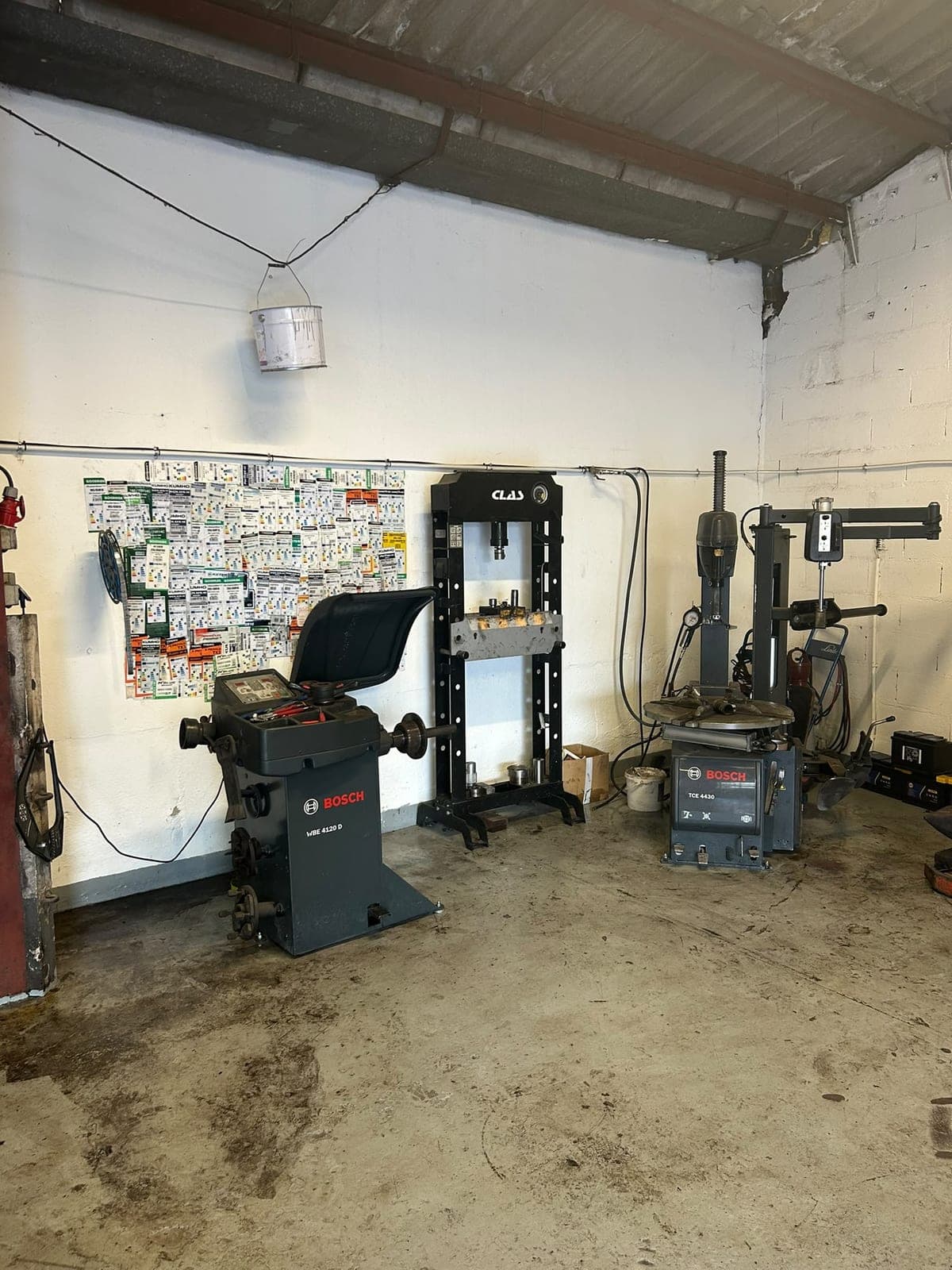 Équilibreuse et démonte-pneu Bosch à côté d'une presse hydraulique, dans l'atelier Kayss Auto.